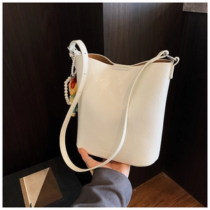 Detail of white leather bucket bag with pearl pendant and adjustable shoulder strap