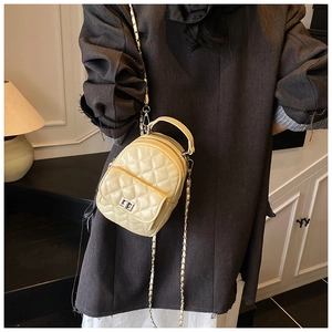 Close-up of beige quilted mini backpack featuring metal chain straps and clasp
