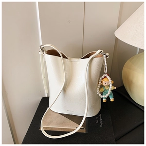 Detail of off-white lychee grain leather bucket bag with cute pearl girl doll charm