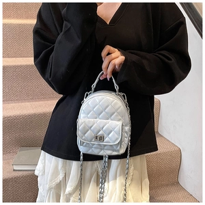 Detail shot of white quilted mini backpack with metal chain straps and classic texture