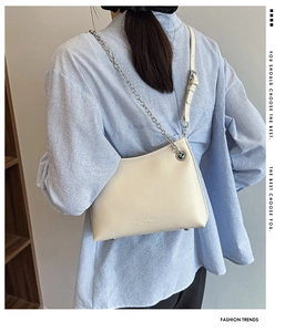 Détail du sac bandoulière crème avec chaîne argentée et clous métalliques sur modèle