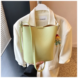 Detail of pistachio green bucket bag featuring a leather texture and cute doll pendant