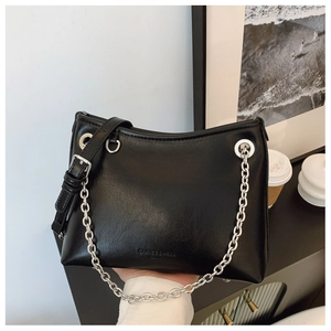 Détail du sac seau noir en cuir avec chaîne argentée et logo gaufré élégant