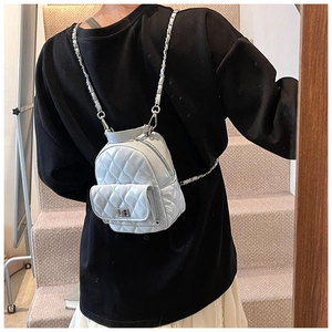 Rear view of model wearing a white quilted mini backpack with silver chain straps