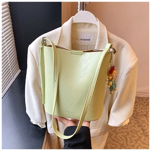 Detail of pistachio green pleated bucket bag with MUDUO logo and cute charm pendant