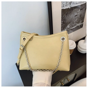 Détail du sac seau jaune clair avec chaîne argentée et logo minimaliste élégant