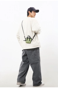 Mini sac à bandoulière vert porté par un mannequin homme en tenue streetwear décontractée