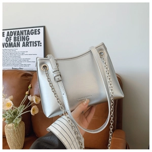 Détail du sac bandoulière argenté métallisé avec chaîne en métal et logo sur cuir