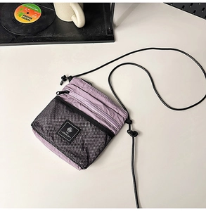 Lavender nylon crossbody bag with black mesh pocket and adjustable cord shoulder strap