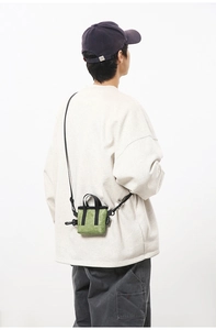 Détail du sac bandoulière plissé vert avec sangles noires porté par un mannequin décontracté