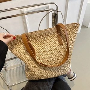 Détail du sac cabas en paille tressée avec poignées en cuir marron et fermeture éclair
