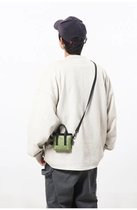 Détail arrière d'un mini sac bandoulière vert olive porté par un mannequin sur blanc