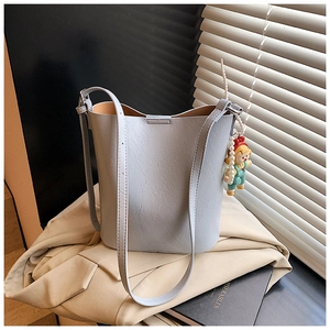 Detail of light blue leather bucket bag with litchi texture and cartoon pearl charm