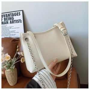 Détail du sac seau en cuir blanc crème avec chaîne argentée et logo de la marque