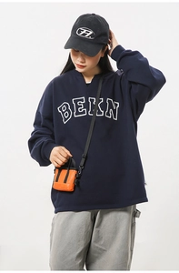 Détail d'un sweat bleu marine style urbain avec imprimé BEKN et mini sac orange vif
