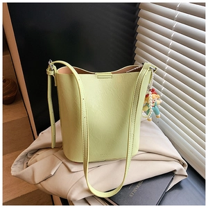 Detail of avocado green bucket bag with wrinkled leather texture and pearl charm