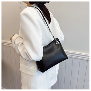 Détail d'un sac seau noir en similicuir avec chaîne argentée et garniture métallique