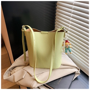 Detail view of a pale green bucket bag with a pearl doll charm and MUDUO embossed logo