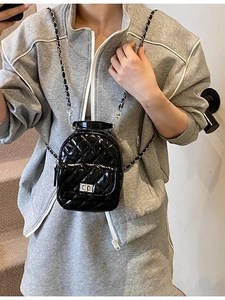 Chic black patent leather quilted mini backpack with metal chain strap on model