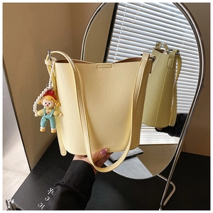Detail of beige bucket bag with litchi texture leather, pearl chain and doll pendant