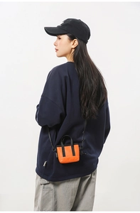 Gros plan d'un mini sac bandoulière en nylon orange vif avec poignée et sangle noires