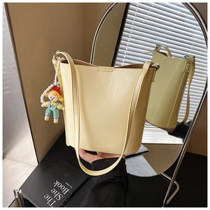 Detail of yellow leather bucket bag with MUDUO embossed logo and beaded doll pendant