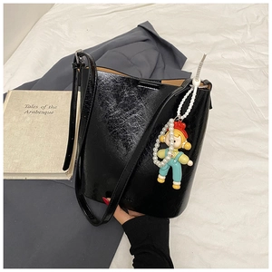 Detailed macro view of black oil wax leather bucket bag with cute doll pendant