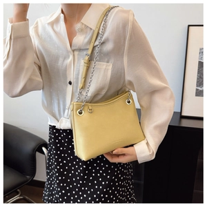 Détail du sac bandoulière croissant jaune clair avec chaîne argentée et logo de marque