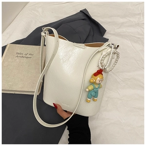 Detail of white bucket bag featuring NIDUO branding, pearl strap and a cute doll charm