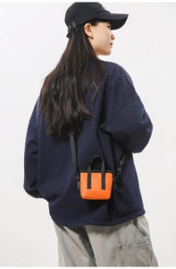 Gros plan sur un mini sac à bandoulière matelassé orange vif avec poignée et étiquette