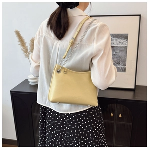 Détail du sac seau en cuir crème avec bandoulière chaîne argentée et pieds en métal
