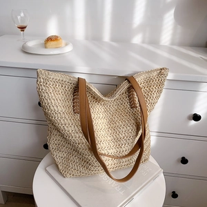 Détail de la texture tressée et de la bandoulière en cuir marron du sac de plage