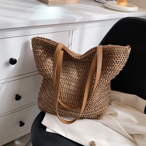 Détail de la texture du sac cabas en paille et des bretelles en cuir marron sur une chaise