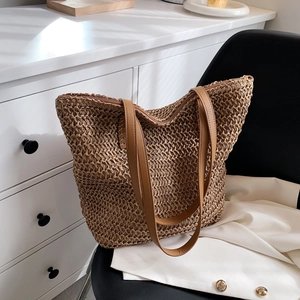 Gros plan d'un sac seau tissé marron avec des anses en cuir sur une chaise