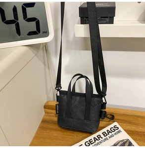 Gros plan sur un sac bandoulière noir avec texture en nylon plissé et étiquette