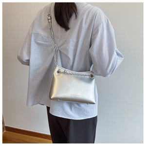 Détail du sac seau argenté avec chaîne porté par un mannequin montrant la texture