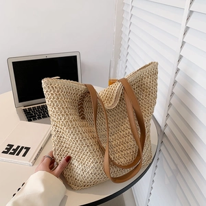 Détail du sac seau en paille tissée avec lanières en cuir marron et fermeture éclair