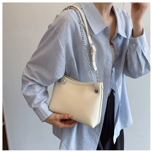 Détail du sac seau blanc crème avec bandoulière chaîne argentée sur chemise rayée