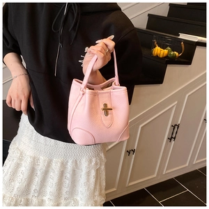 Detail of pink bucket bag featuring lychee texture leather and a gold T-bar twist lock