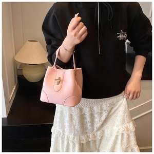 Detail of pink pebbled leather bucket bag with gold twist-lock and reinforced base