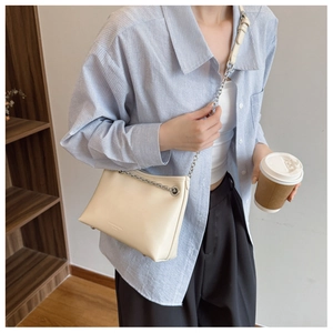 Détail du sac à bandoulière crème avec chaîne en métal argenté et garniture en cuir