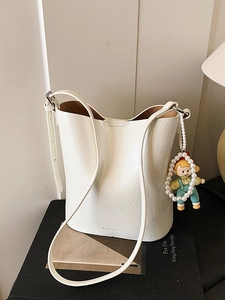 Minimalist beige bucket bag with leather pleats and a cute pearl charm accessory