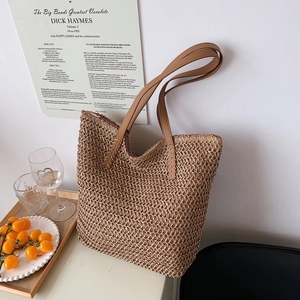 Détail d'un sac seau tressé ajouré avec anses en cuir marron pour les vacances
