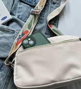 Detail van het voorvak met rits op de beige oxford crossbodytas voor een smartphone