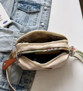 Detailweergave van beige oxford stoffen tas met geborduurde bloemenband en binnenvoering