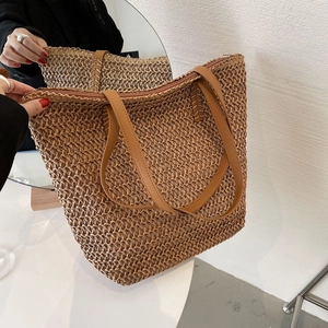 Détail du sac cabas en paille tissée avec anses en cuir marron et fermeture éclair