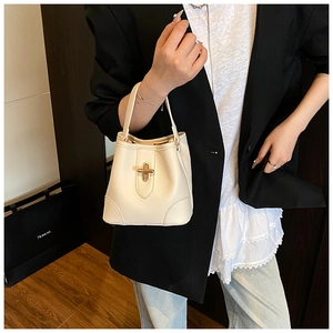 Detail shot of cream white grain leather bucket bag with golden metal twist lock closure