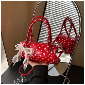 Close-up of red polka dot cylinder handbag with pearl bow and glossy patent finish