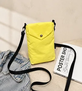 Dettaglio mini borsa a tracolla in nylon giallo con bottone automatico in metallo