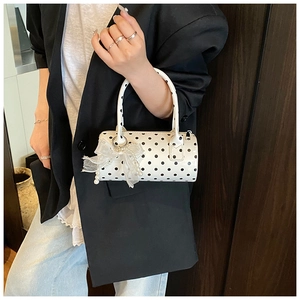 Close-up of polka dot cylinder handbag with lace bow and pearl charm detail